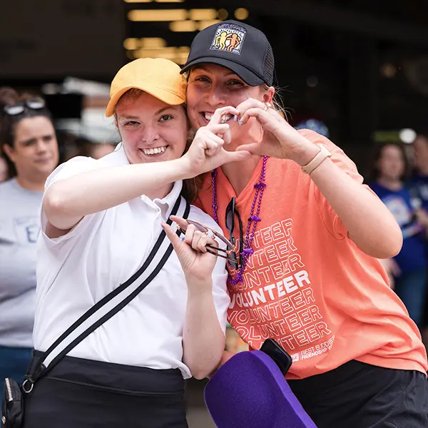 two female attendees making heart sign with their hands help together